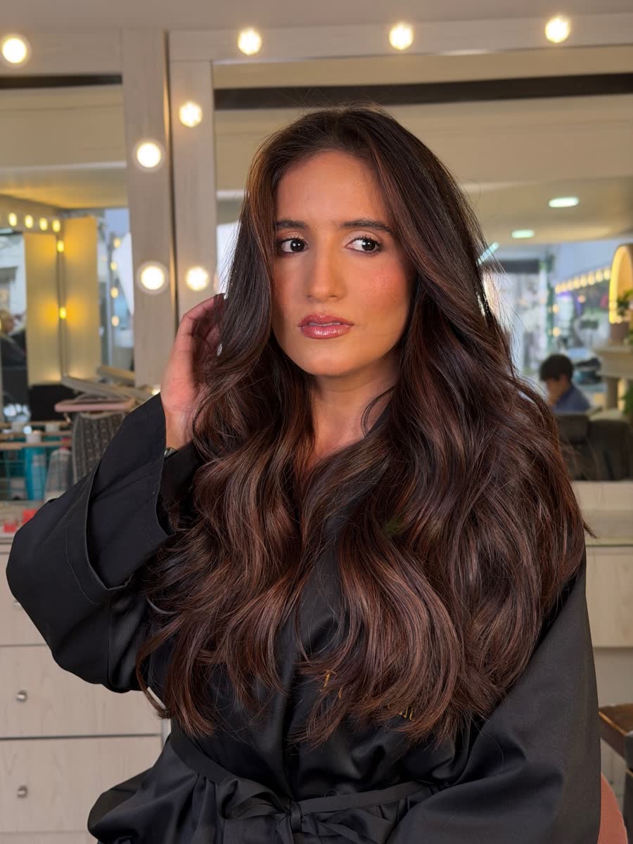 Clienta con ondas brunette frente al espejo