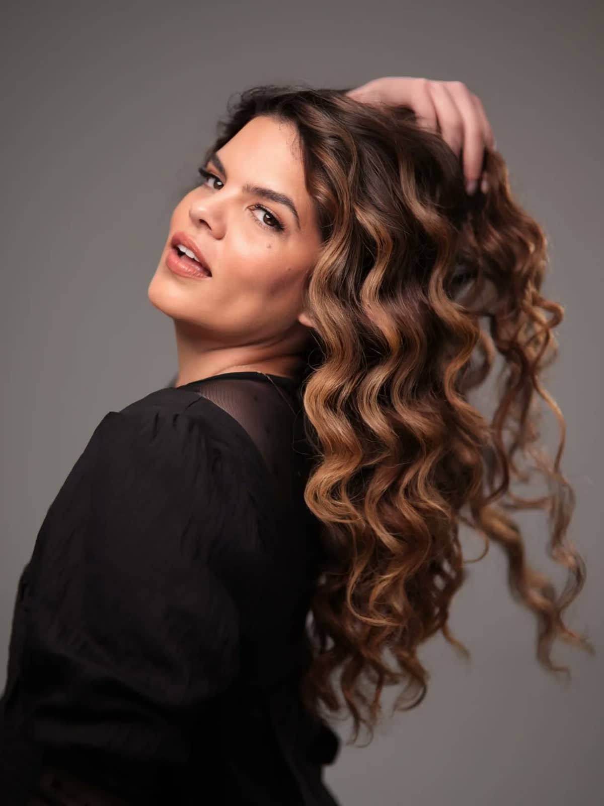 Modelo con rizos largos en balayage chocolate y caramelo, look 'Evolución'
